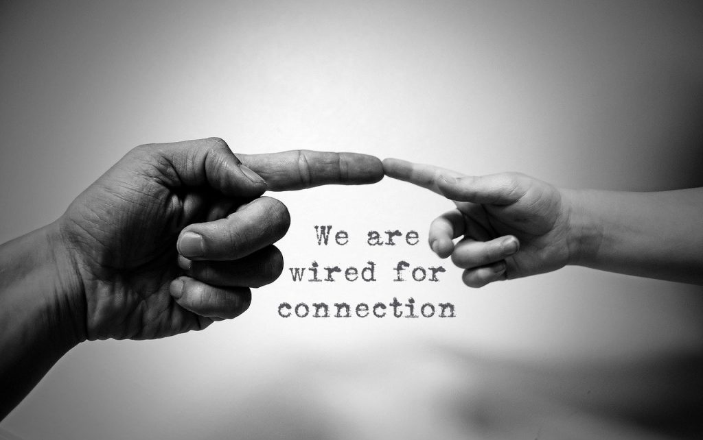 We are wired for connection. Two hands extended to reach to each other on blog about zielschmerz