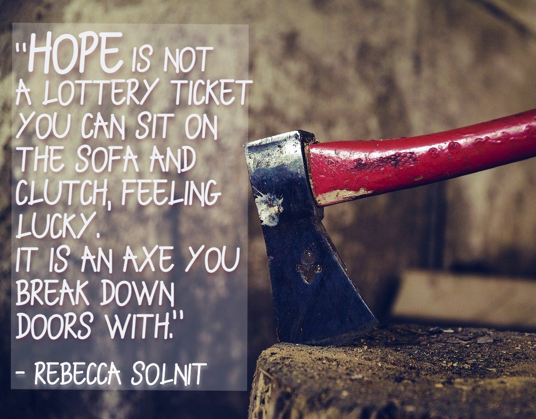 hope is not a lottery ticket you can sit on the sofa and clutch, feeling lucky. It is an axe you break down doors with. Quote by Rebecca Solnit on picture of an axe stuck in a log.